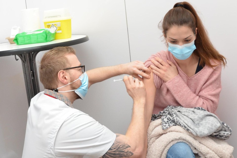 Een jonge vrouw wordt gevaccineerd. 