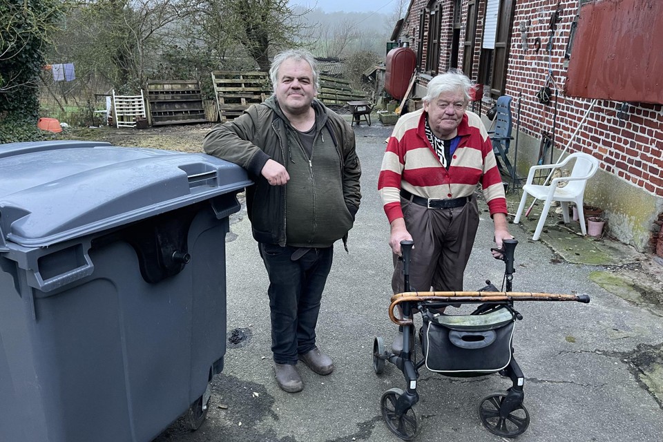 Marc en zijn vader Joël Martain bij een afvalcontainer op het erf van hun boerderij. 
