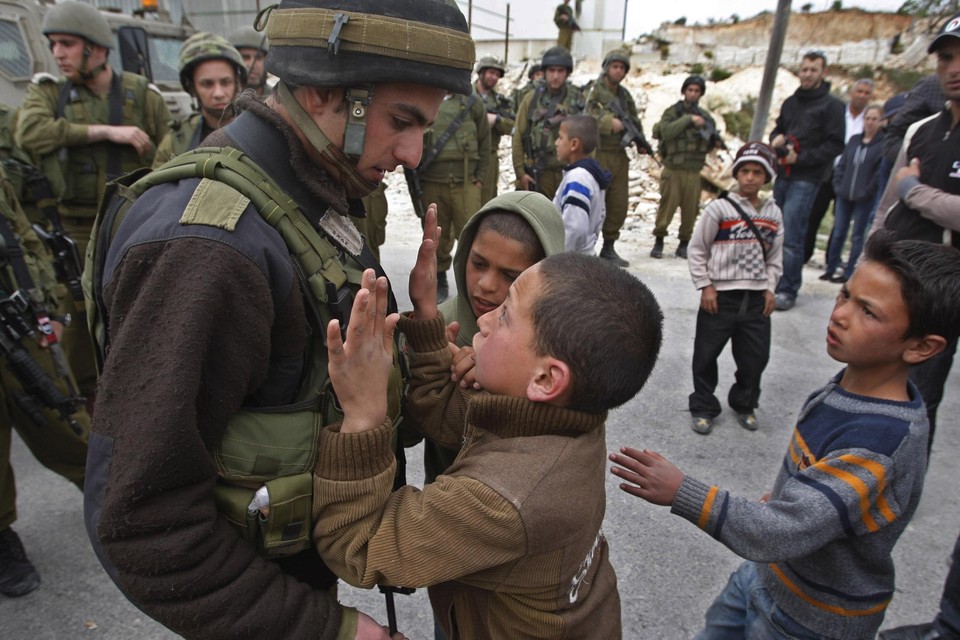 Een Palestijns kind probeert voorbij  een Israëlische agent te raken  tijdens een betoging over de controversiële grensmuur in Maasarah, in 2009. 