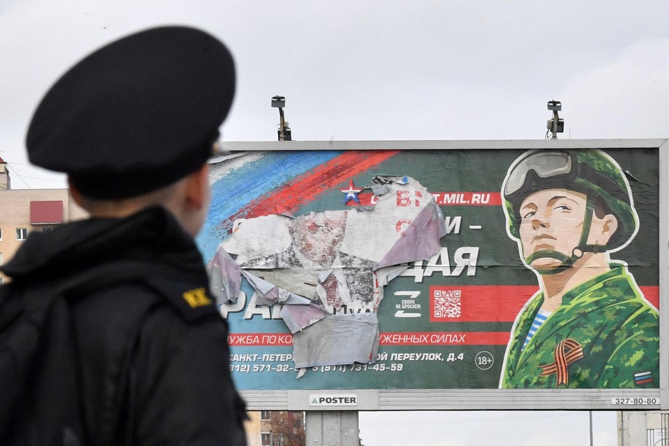 Een kadet in Sint-Petersburg kijkt naar een vernielde poster die oproept om zich als vrijwilliger te melden. Na twee weken is de gedeeltelijke mobilisatie in Rusland nog altijd een puinhoop en zorgt die voor onvrede en frustratie.  