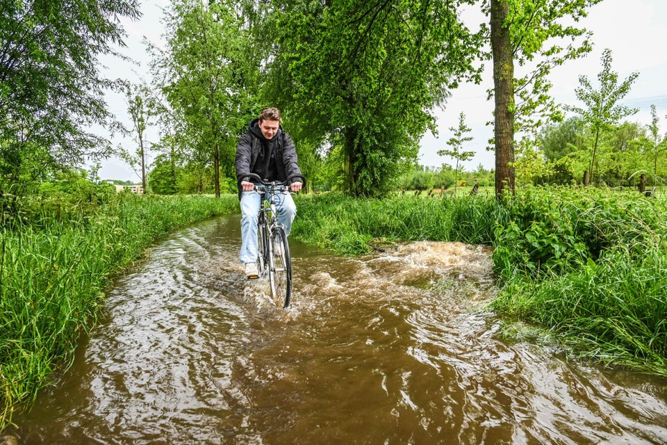 Het water kolkt omhoog uit een riooldeksel aan het fietspad langs de Universiteitslaan