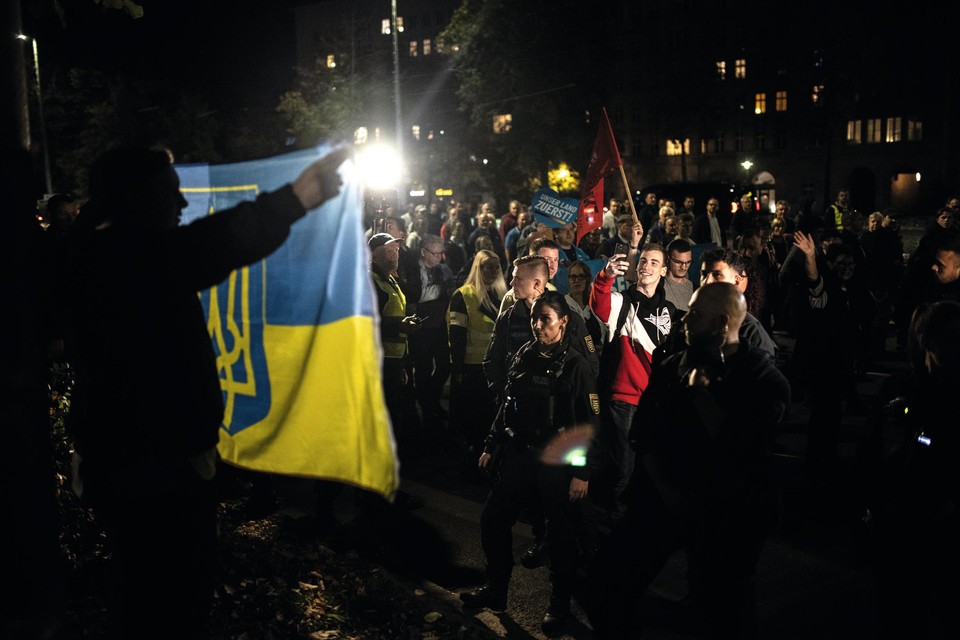 Een linkse betoger houdt een Oekraïense vlag in de lucht langs de route die de rechtse protesteerders elke maandag afleggen. Politie houdt de wacht rond hem, om escalaties te voorkomen. 