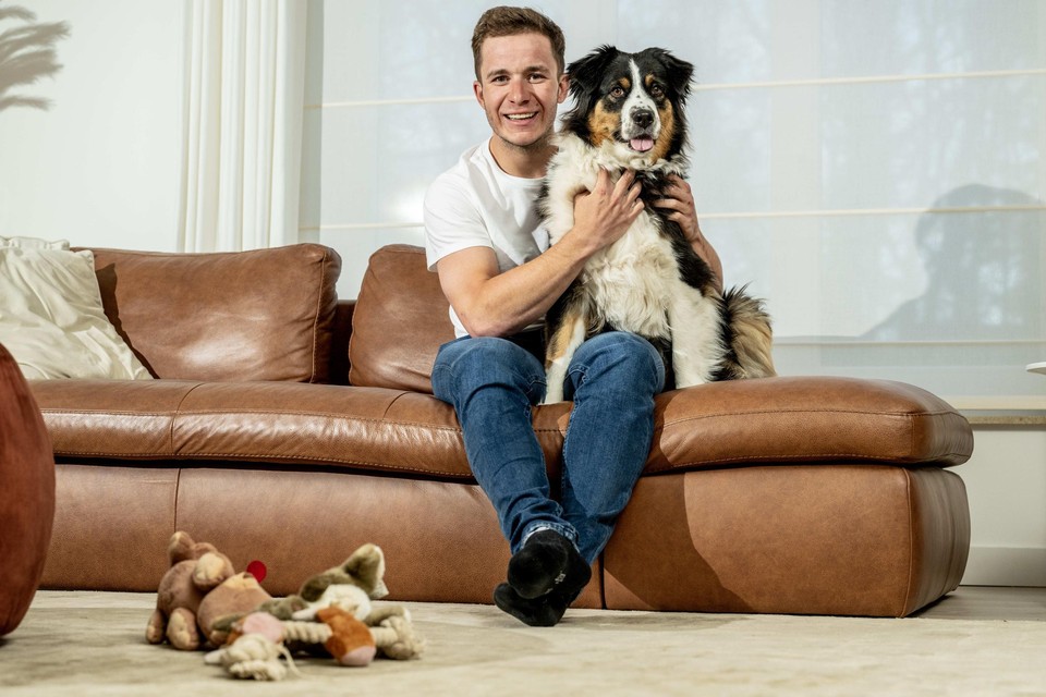 Gerben Thijssen, met de tweejarige Australische herder Ukki, in de sofa van het ouderlijke huis in Genk.