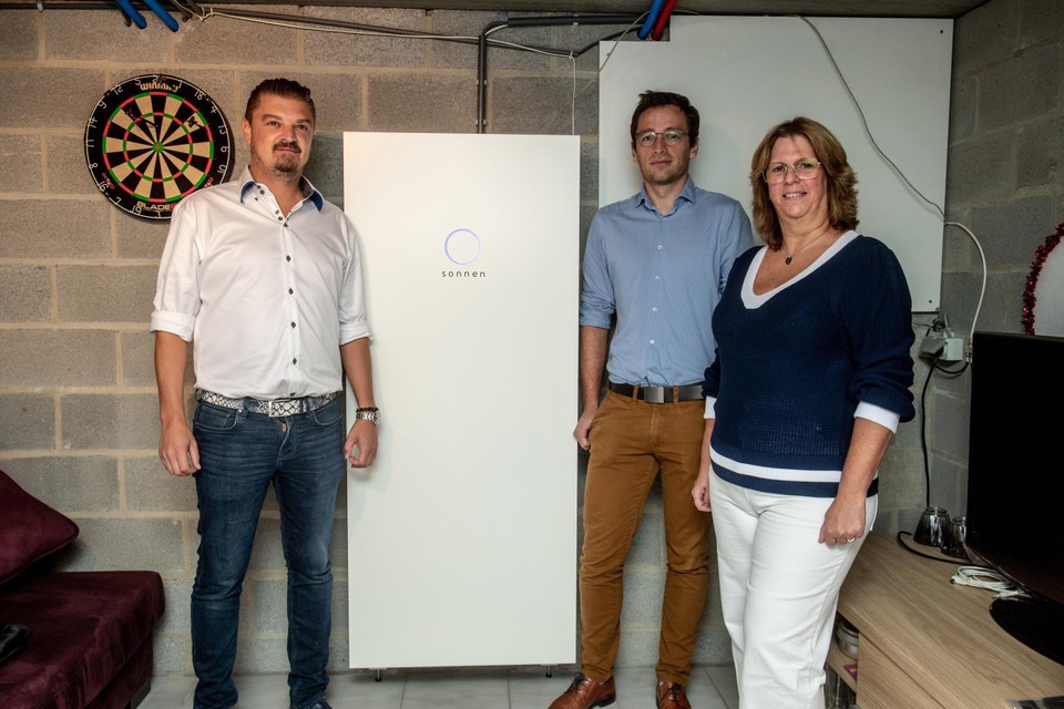 Ben Kunnen van Opteco (links) en Arno Motté van Elia bij de nieuwe thuisbatterij van Patricia Fyon (rechts) in Riemst. 