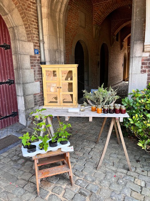 Eén van de bewoners van het Koetshuis stelt lekkernijen en plantenstekjes te koop aan eerlijke passanten die geld kunnen achterlaten. 