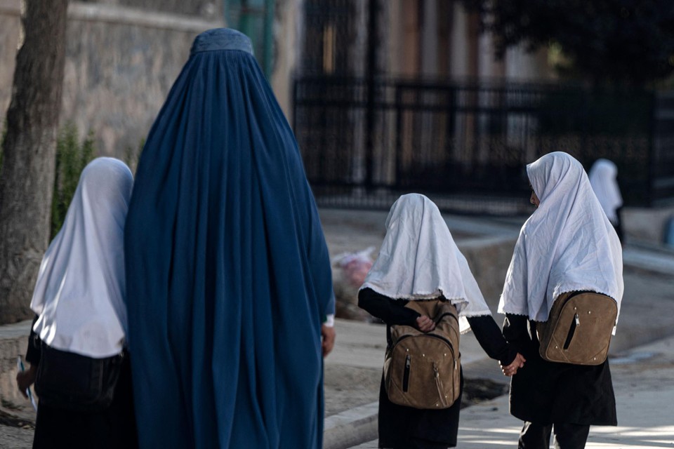 Een Afghaanse moeder wandelt met haar kinderen naar school 