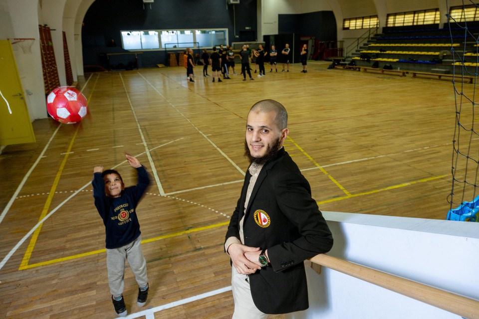 Ibrahim Emsallak in de sportzaal, in de achtergrond speelt zijn zoontje met een bal en krijgt een groepje boksers les.