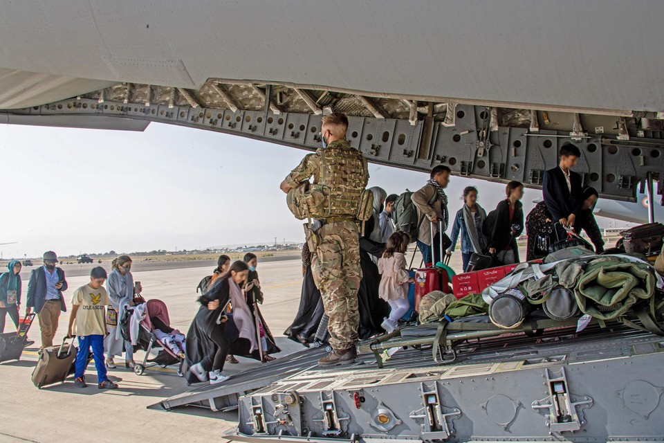Britse soldaten helpen burgers en Afghanen die de Britten geholpen hebben evacueren. 