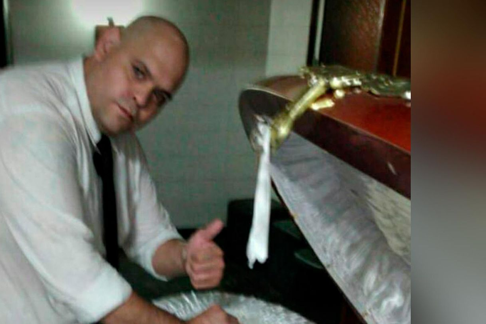 De intussen ontslagen medewerker van het funerarium bij de kist van Maradona. De foto is afgesneden omdat het lichaam te zien was. 