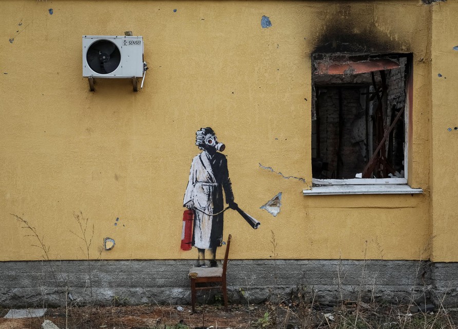 Een vrouw in een badjas met een gasmasker en een brandblusser in Hostomel. 