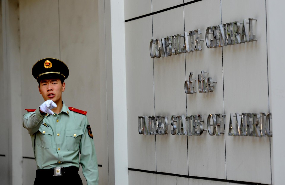 Een Chinese soldaat gebaart dat er geen foto mag getrokken worden van het Amerikaanse consulaat in Chengdu. 