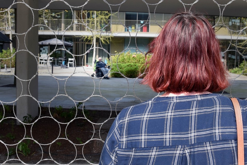 Een familielid praat op afstand via het hek met een bewoner van het OCMW-woonzorgcentrum Kapittelhof in Lommel. Het rusthuis liet woensdag al op eigen initiatief iedereen testen. 