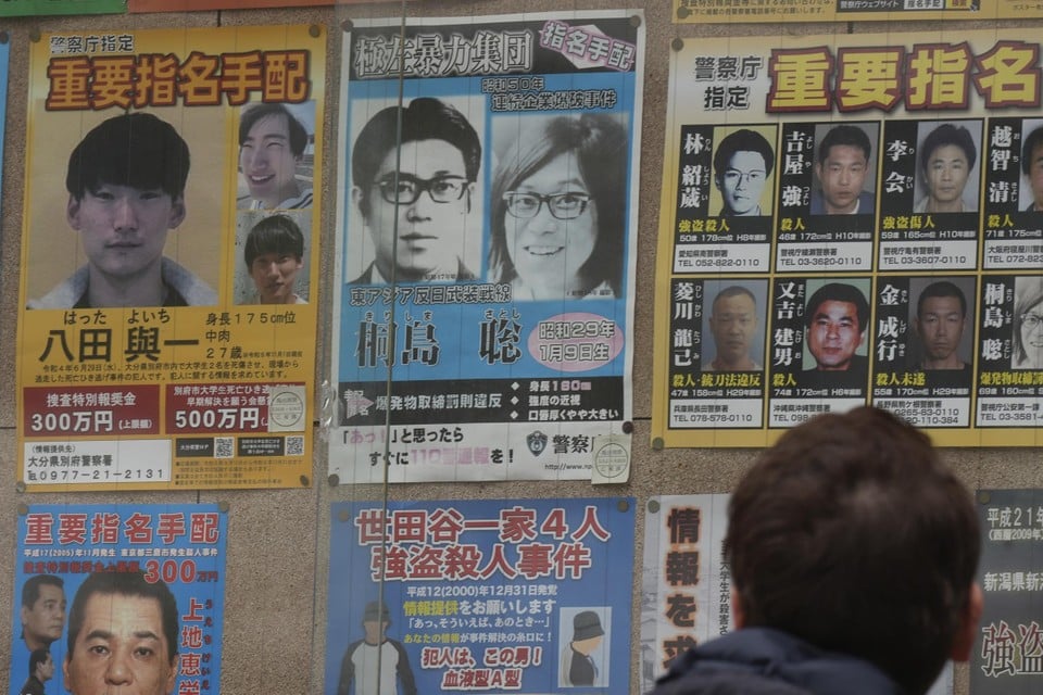 Een gezocht-poster met Satoshi Kirishima (blauwe poster bovenaan, rechts), die na bijna 50 jaar als voortvluchtige in het ziekenhuis overleed. Foto: Eugene Hoshiko/AP