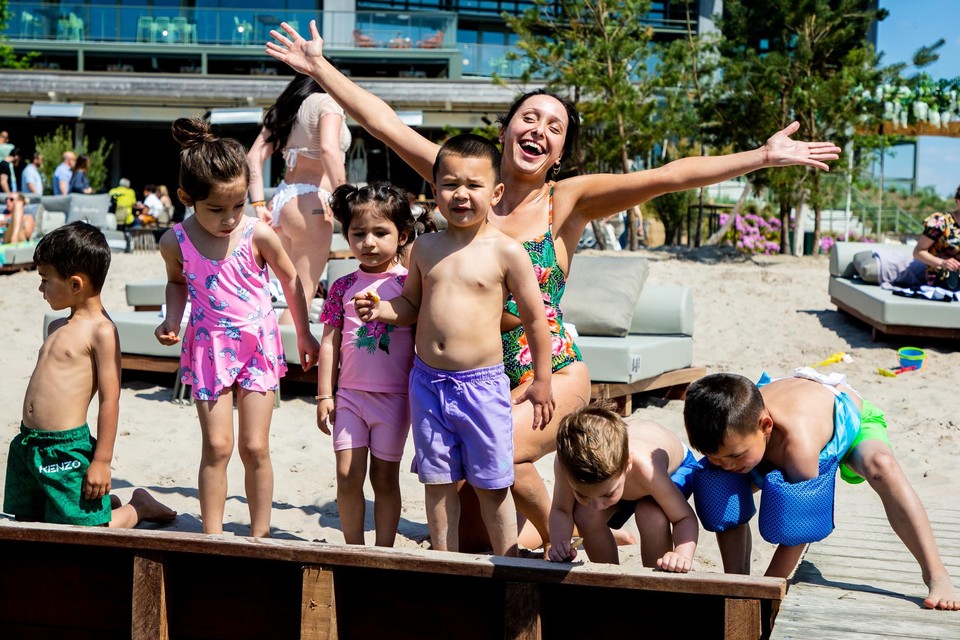 Una geniet met de kinderen van de eerste zomerzon op het strand van het Terhills Resort in Dilsen-Stokkem. 