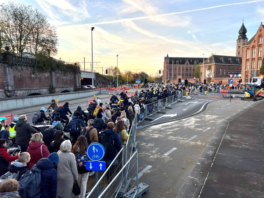 Een mensenzee van fietsers en voetgangers wacht om het kruispunt aan Nekkerspoel over te steken.  