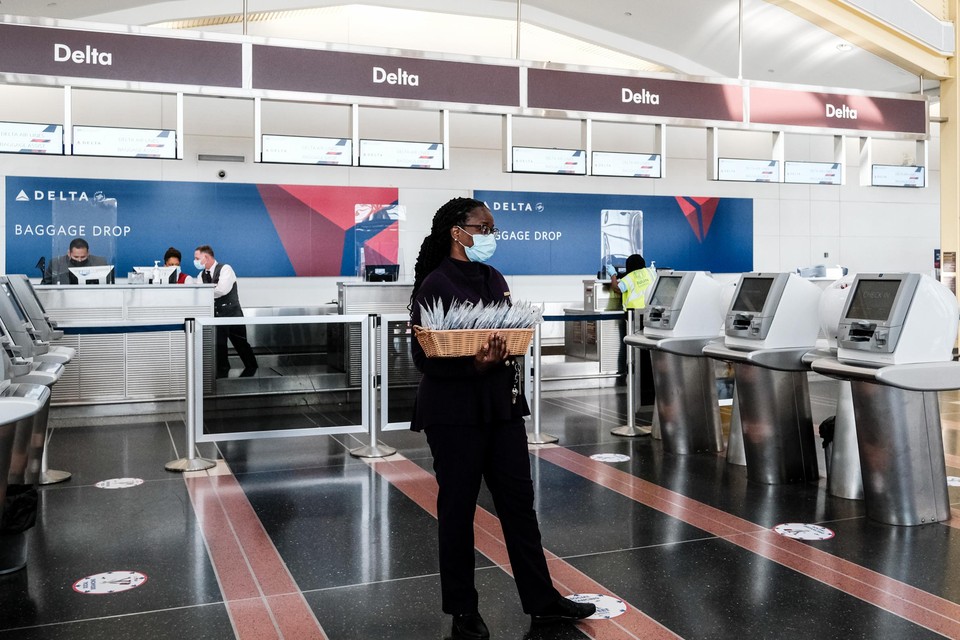 Een medewerker van Delta Airlines deelt mondmaskers uit. 