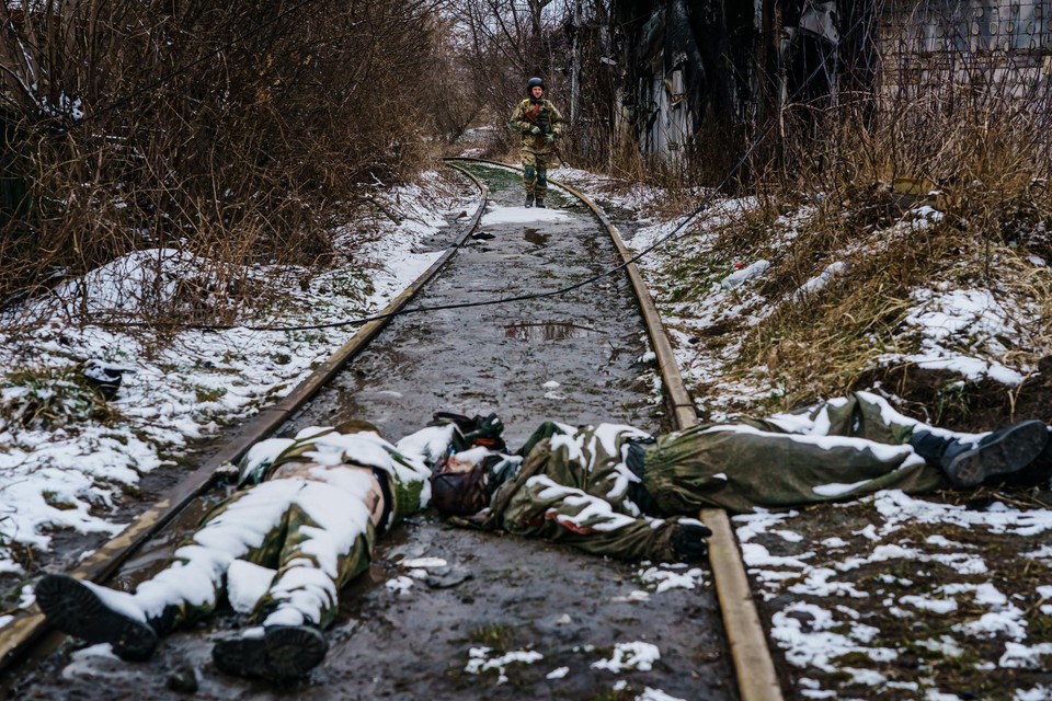 Een Oekraïense soldaat stapt naar gesneuvelde Russische strijders in Irpin.  