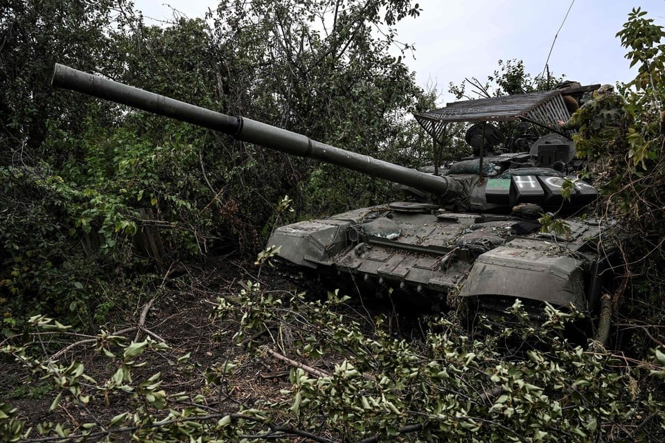 Een Russische tank staat verdekt opgesteld in het struikgewas.