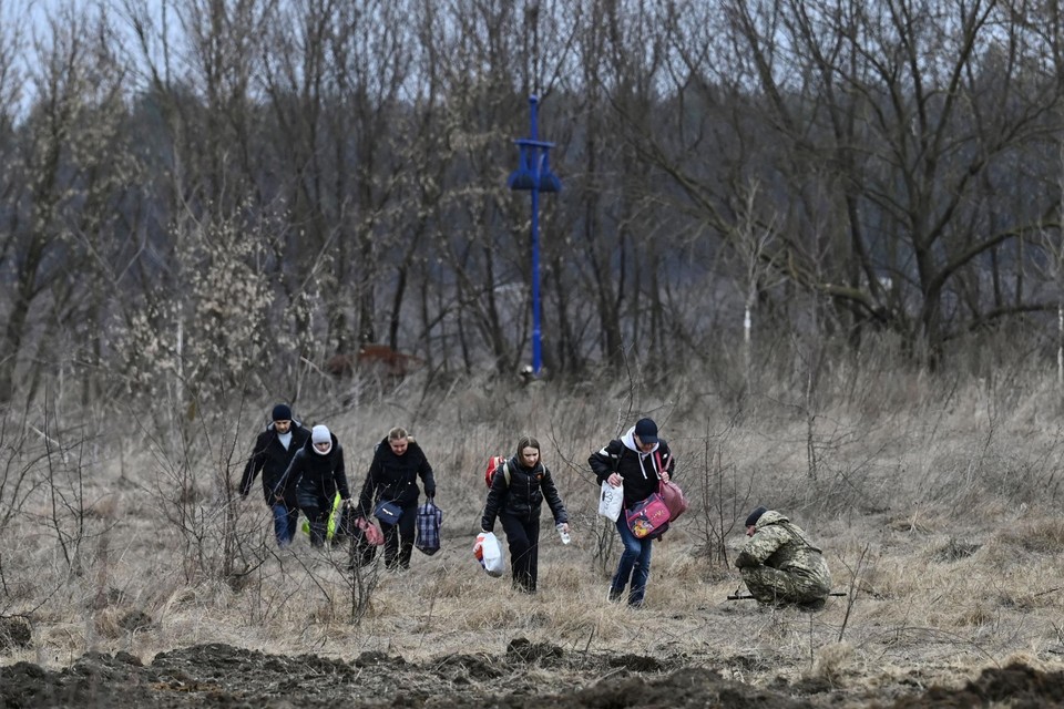 Een familie door de bossen op de vlucht, geflankeerd door een Oekraïense soldaat. 