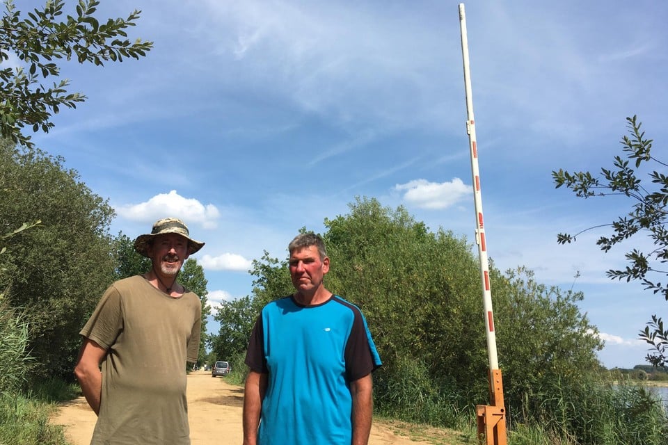 Vissers Peter Asnong en Karel Vanderstraeten bij de slagboom die al 35 jaar voor wrevel zorgt, maar volgens het politiereglement dicht moet. 
