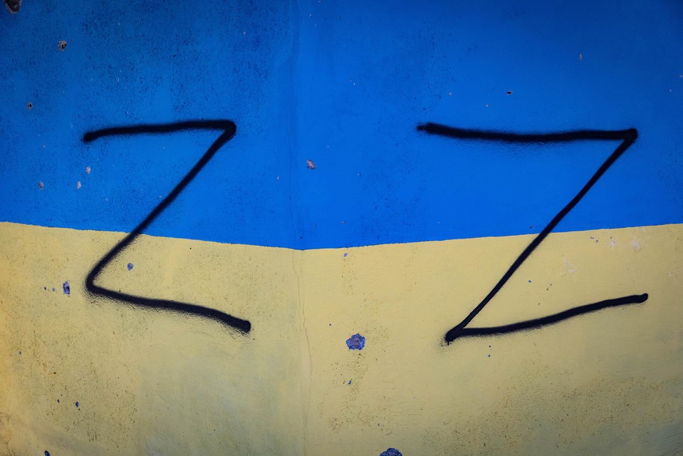 Russen schilderden het Z-symbool als oorlogsteken op een muur met de Oekraïense vlag. 