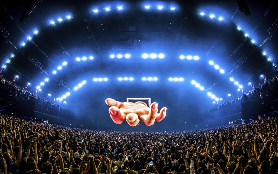 Een holografische hand strekt zich uit boven het publiek van Tomorrowland 2022. 