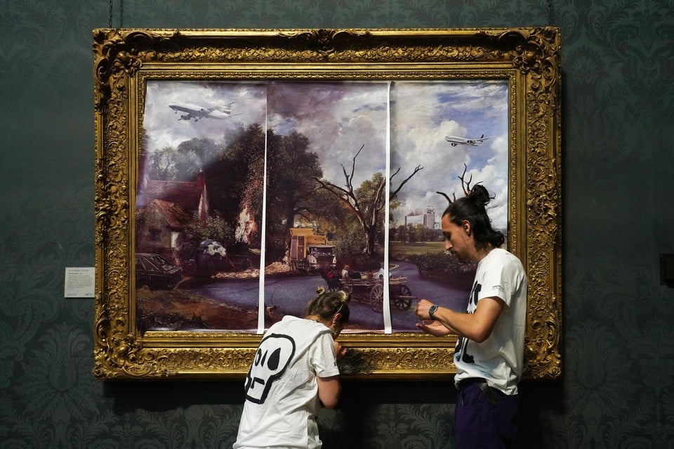 Twee activisten, hier aan de slag met de ‘Hooiwagen’ van John Constable, beschrijven hun werkwijze als “geweldloos burgerlijk verzet” in de Britse National Gallery. 