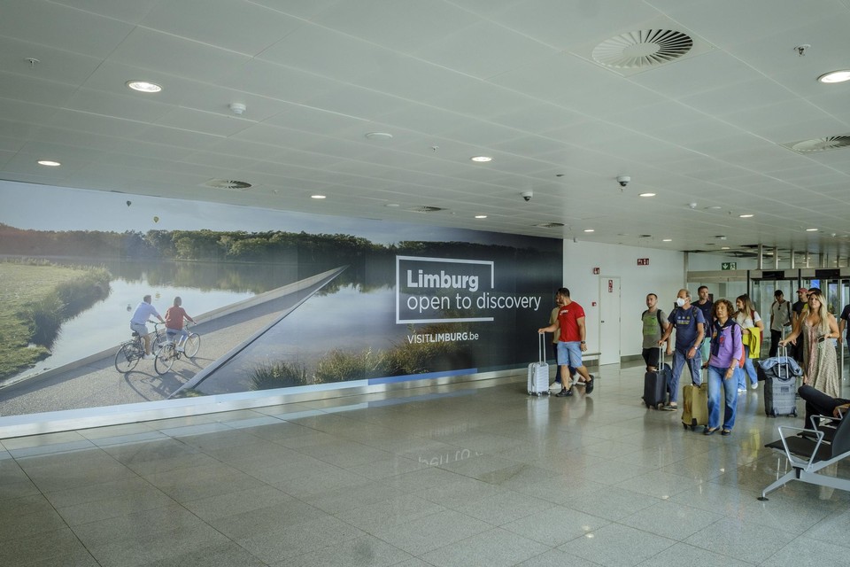 Het opvallende reclamepaneel hangt op een plek waar deze zomer ruim 3 miljoen passagiers richting de bagagehal van Brussels Airport wandelen.